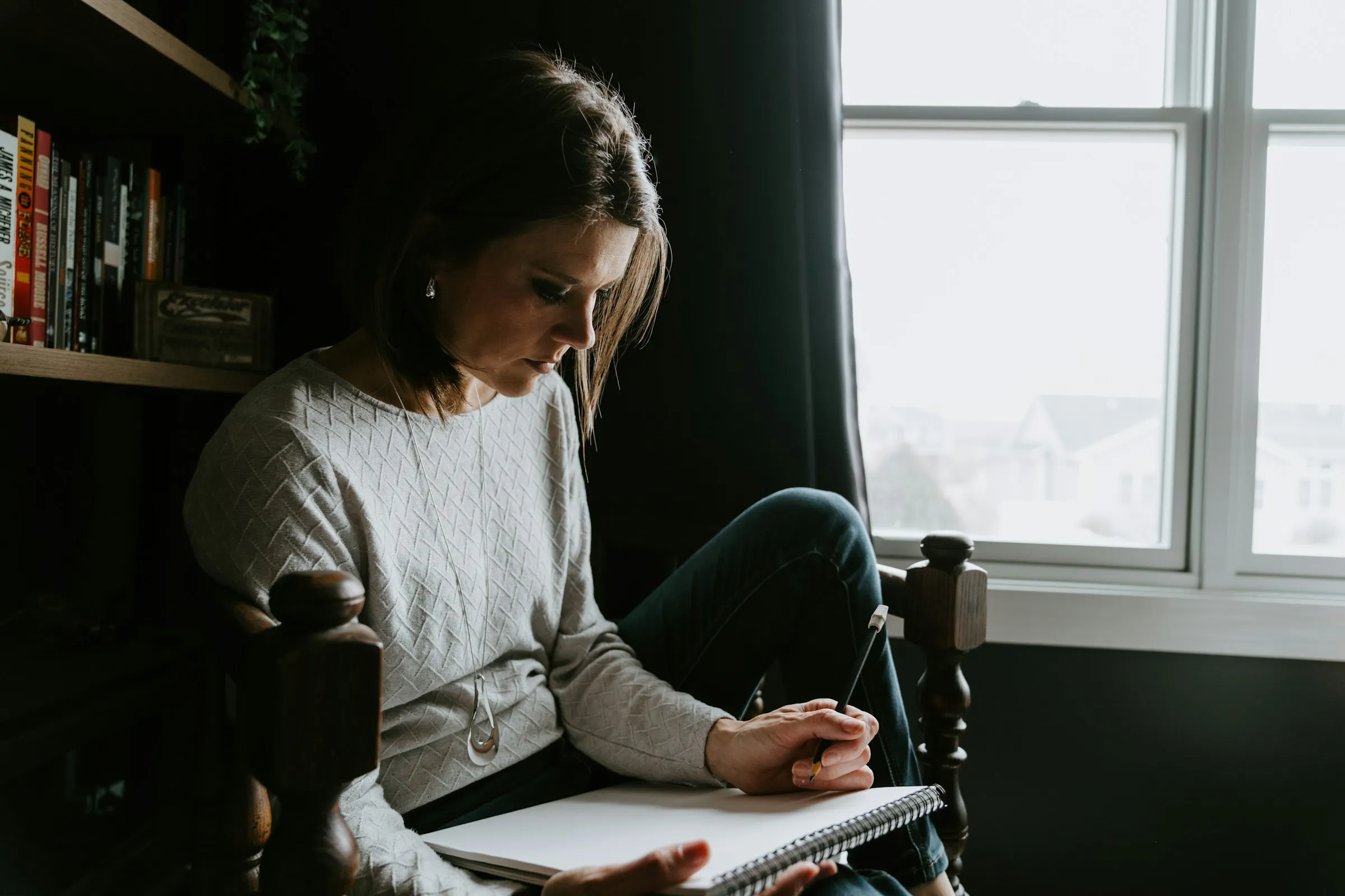 A woman reading through her notes in an armchair by the window